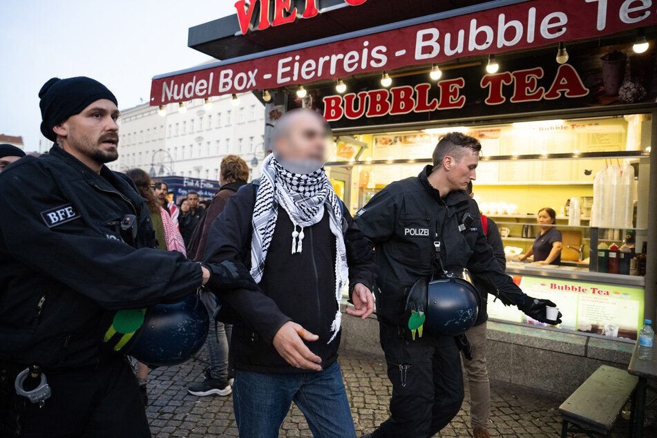 Auf dem Herrmannplatz in Berlin-Neukölln führt die Polizei einen Mann mit Palästina-Tuch um den Hals ab.