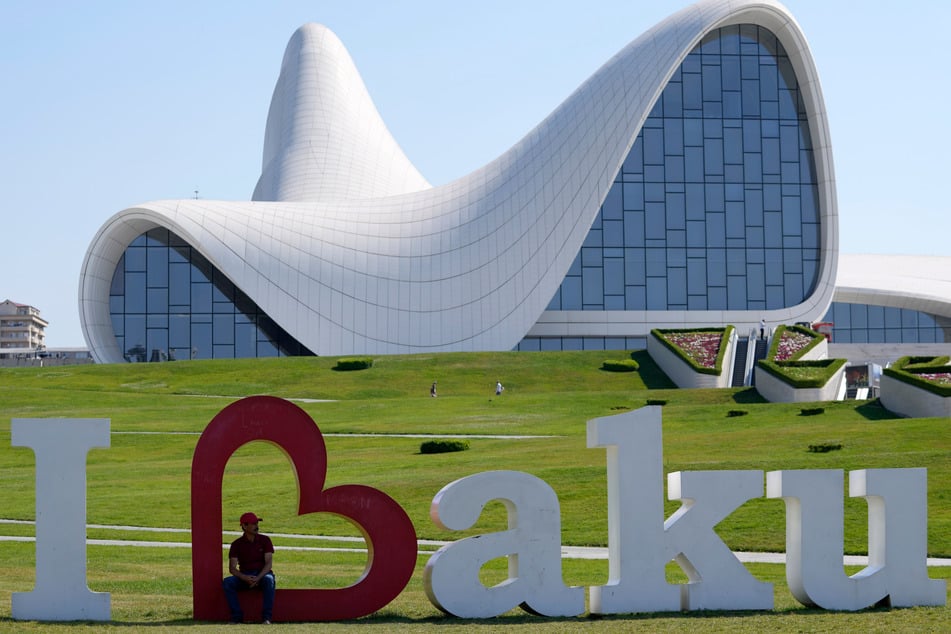 Baku: Ein Mann sitzt in einem übergroßen Herz vor dem Heydar-Aliyev-Kulturzentrum vor der bevorstehenden Fußball-Europameisterschaft.
