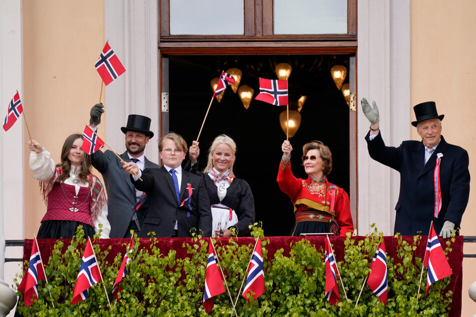 König Harald V. von Norwegen (83, r-l), Königin Sonja (82), Kronprinzessin Mette-Marit (46), Prinz Sverre Magnus (14), Kronprinz Haakon (46) und Prinzessin Ingrid Alexandra (16) winken während der Feierlichkeiten zum Verfassungstag von ihrem Balkon.