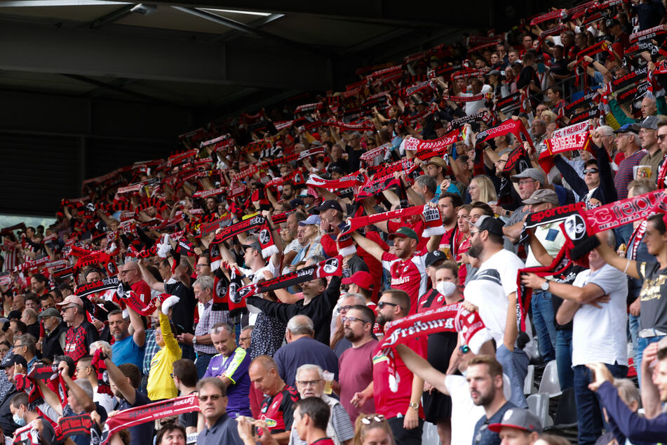 Fans des SC Freiburg halten vor dem Anpfiff im Dreisamstadion ihre Schals hoch und stimmen sich auf die Begegnung gegen den 1. FC Köln ein.
