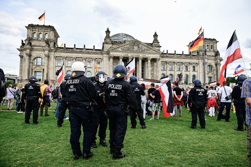 Teilnehmer einer Demonstration gegen die Corona-Maßnahmen stehen mit Reichsflaggen vor dem Reichstag