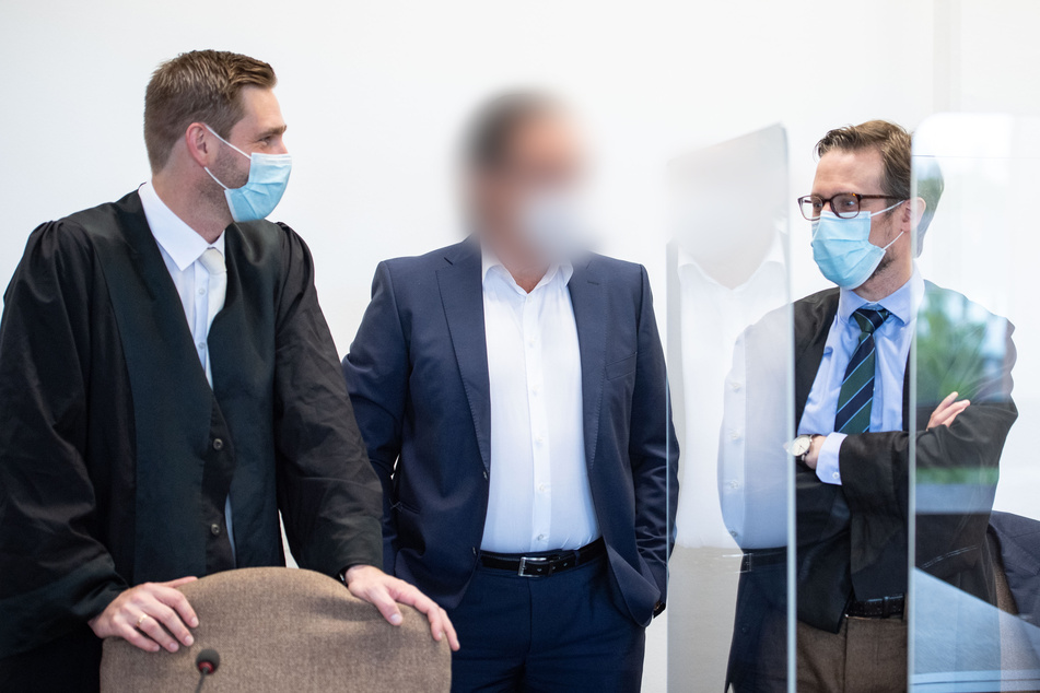 Einer der Angeklagten (m.) steht beim Prozessauftakt im Landgericht Köln neben seinen Verteidigern Jan Allendorf (l.) und Christian Mertens.