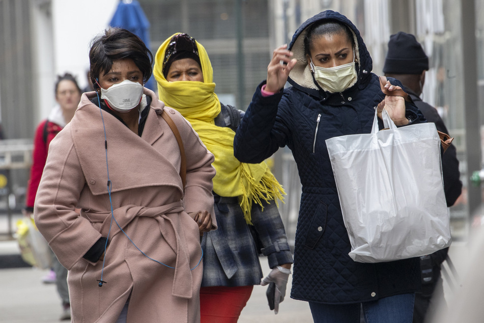 Afroamerikanische Frauen tragen auf ihrem Weg durch die 34th Street in New York eine Gesichtsmaske und einen Schal, um Mund und Nase zu schützen. Rapide steigende Zahlen von Corona-Infektionen und Todesfällen schrecken die USA auf.