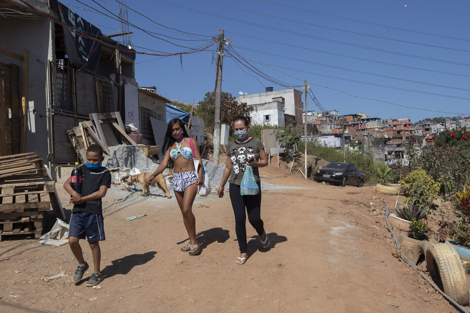 Brasilien, Sao Paulo: Anwohner gehen durch das Stadtviertel Brasilandia. Nach Angaben der Behörden hat Brasilandia mit über 280 000 Einwohnern die höchste Covid-19-Sterblichkeitsrate der Stadt.