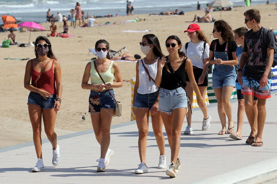 Menschen spazieren am Strand von Biarritz in Südwestfrankreich entlang. Französische Präfekturen können nun auch vereinzelt Maskenpflicht an der frischen Luft anordnen. (Archivbild)