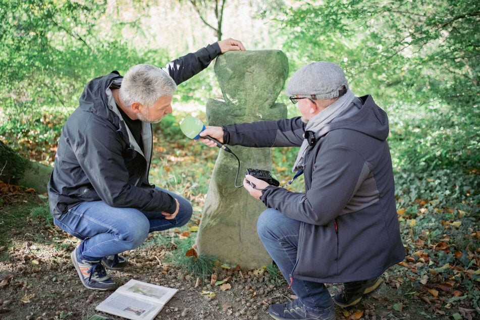 Der experimentelle Archäologe Mario Sempf (55, l.) zeigt Autor Mario Süßenguth (54) das Sühnekreuz im Großen Garten.