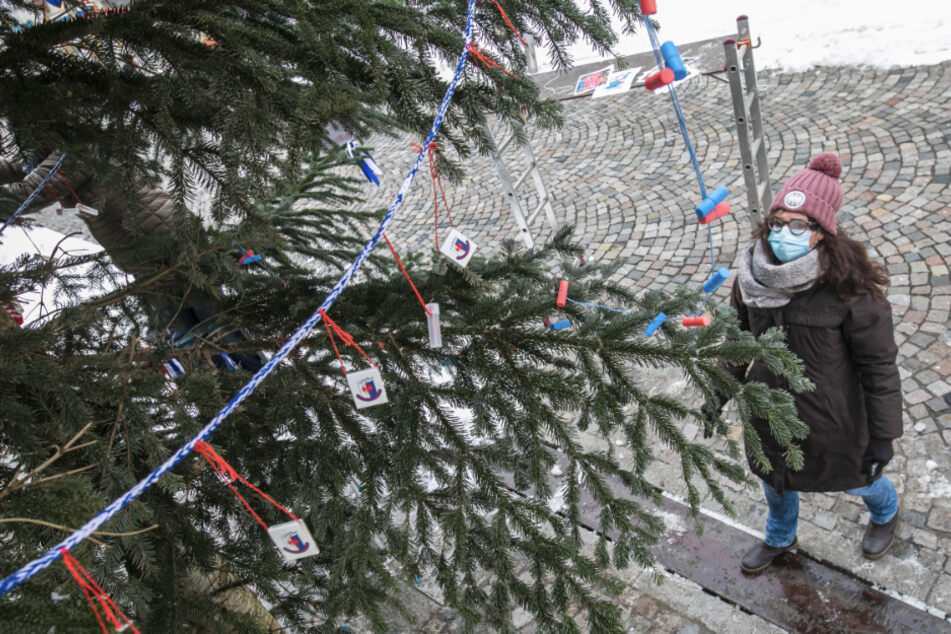 Ein Mitglied der sogenannten "Trommlerwieber" begutachtet die Dekoration an einem der zukünftigen "Fasnetbäume". Aus Weihnachtsbäumen werden Fasnetbäume.