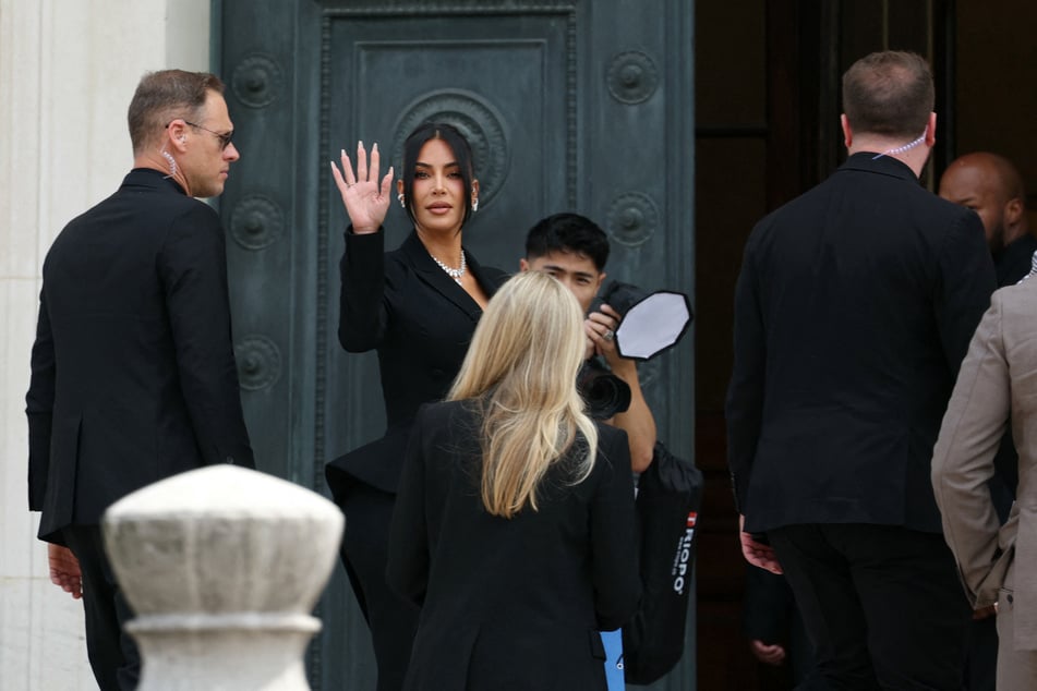 Kim Kardashian waves as she arrives at the Assize Court in Paris for the 2016 robbery trial.