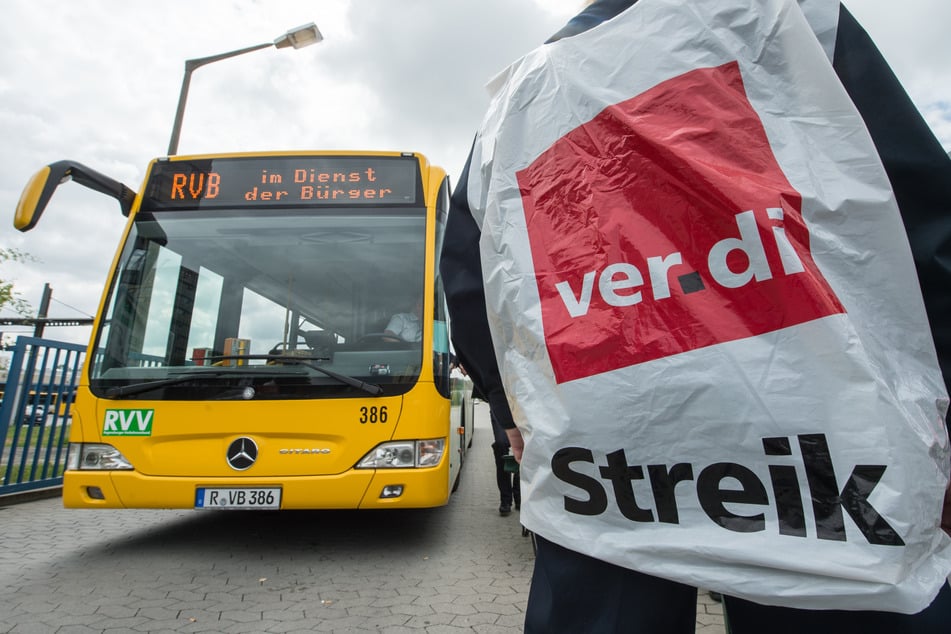 Ein streikender Busfahrer steht vor einem Bus. (Symbolfoto)