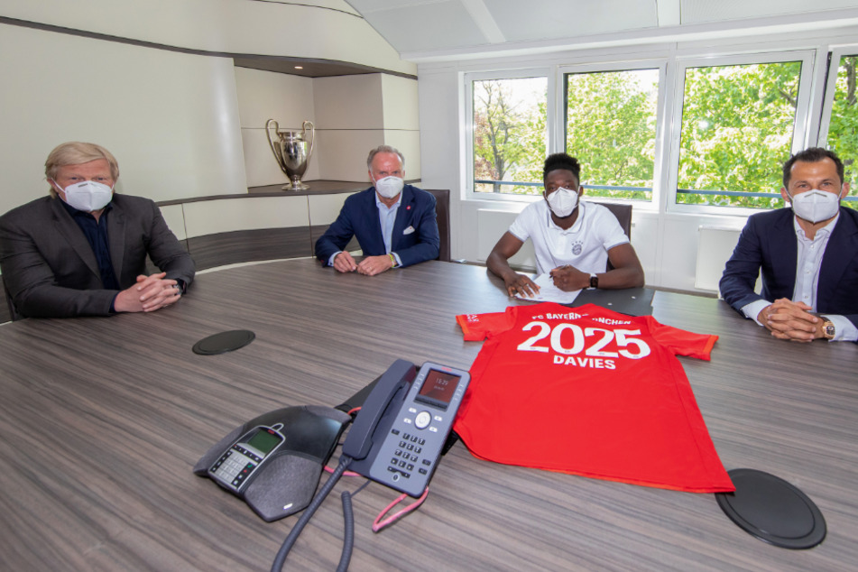 Oliver Kahn (v.l.n.r.), Vorstand des FC Bayern München, Karl-Heinz Rummenigge, Vorstandsvorsitzender des FC Bayern, Alphonso Davies und Sportdirektor Hasan Salihamidzic bei der Vertragsunterzeichnung.