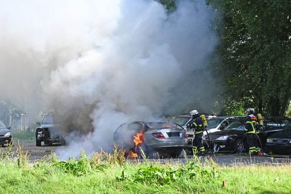 Feuerwehrleute löschen den brennenden Mercedes. Viel blieb von dem Auto am Ende nicht mehr übrig.