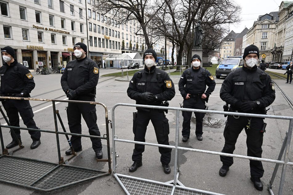 Polizisten stehen zu Beginn der Münchner Sicherheitskonferenz 2022 hinter einem Sperrgitter in der Nähe des Hotel Bayerischer Hof.