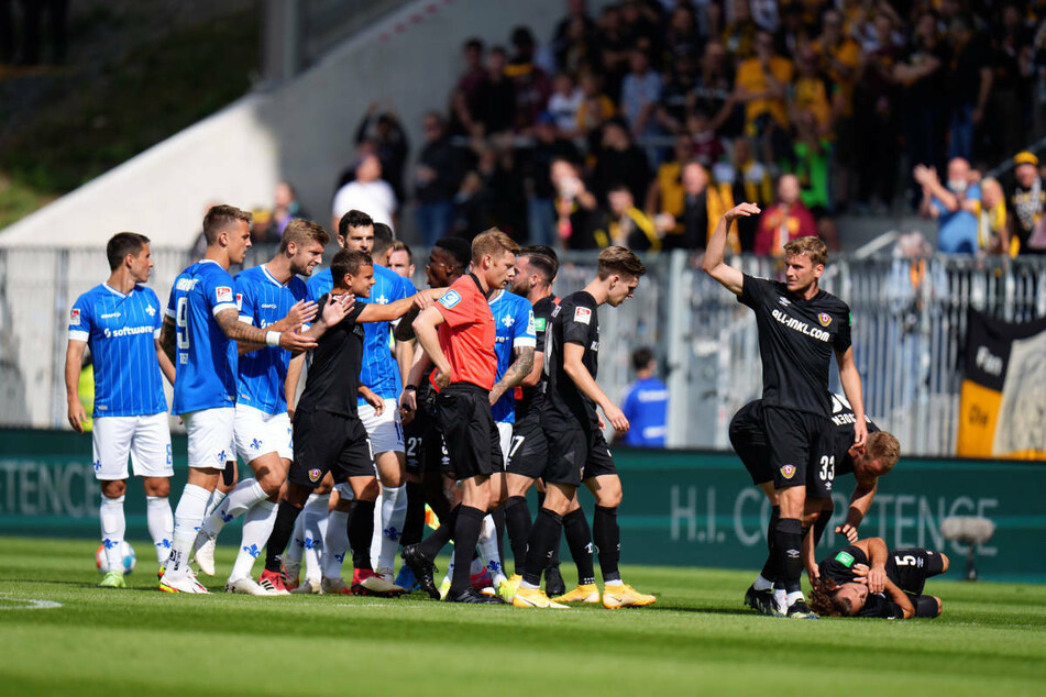Dresdens Yannick Stark (r.) liegt nach dem groben Foul von Fabian Schnellhardt auf dem Boden, Schiedsrichter Christian Dingert greift in die Gesäßtasche zur Roten Karte.