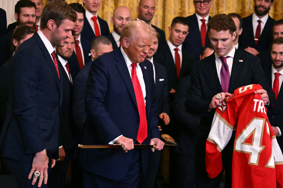 US President Donald Trump is presented with a jersey and hockey stick by players of the NHL 2024 Stanley Cup Champions Florida Panthers, captain Aleksander Barkov (L) and forward Matthew Tkachuk, as Trump welcomes the team to the White House on Monday in Washington, DC.