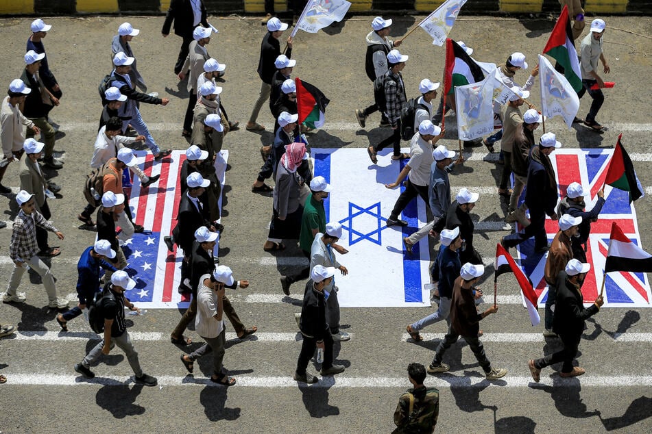 Students walk over depictions of the US, Israeli, and UK flags while marching in a demonstration to show their support for the Houthi movement at the Sanaa University campus in Yemen on July 22, 2026.