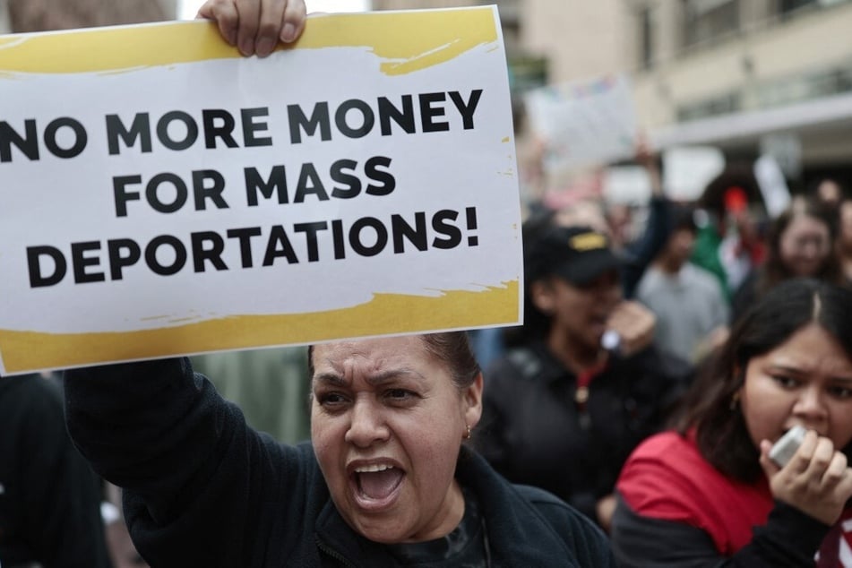 A demonstrator raises a sign reading "No More Money For Mass Deportations" as immigrants' rights supporters march in Los Angeles, California, on March 1, 2025.