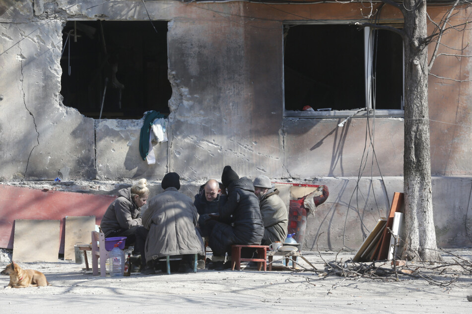 Menschen sitzen vor einem beschädigten Gebäude in Mariupol und bereiten Essen zu. Seit mittlerweile 43 Tagen führt Russland Krieg gegen die Ukraine. Alle aktuellen Entwicklungen aus dem Krisengebiet im TAG24-Liveticker.