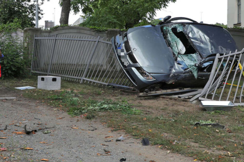 BMW schleudert gegen Baum und bleibt auf Polizeizaun hängen