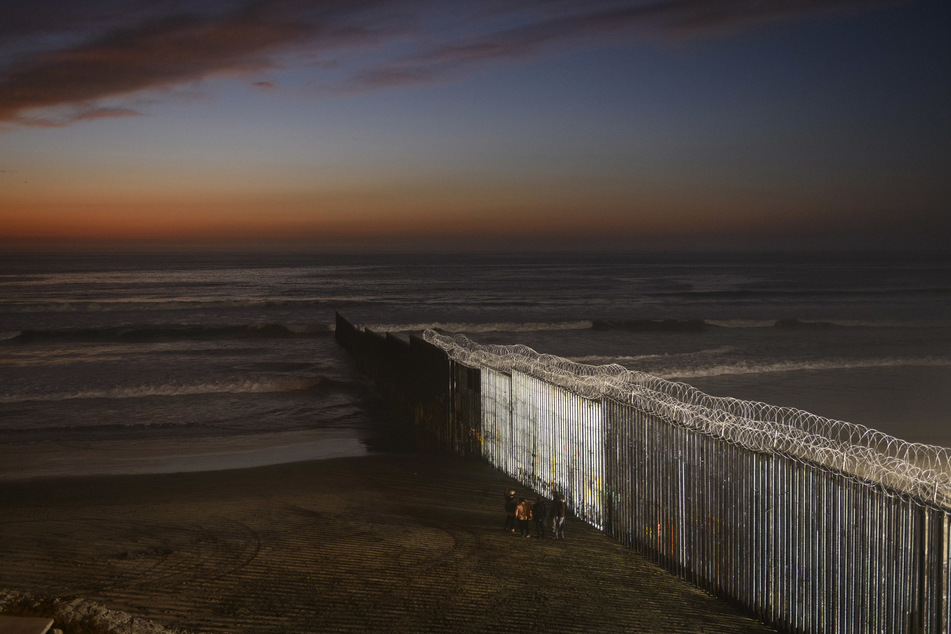Menschen stehen an der Grenzmauer zwischen Mexiko und San Diego.