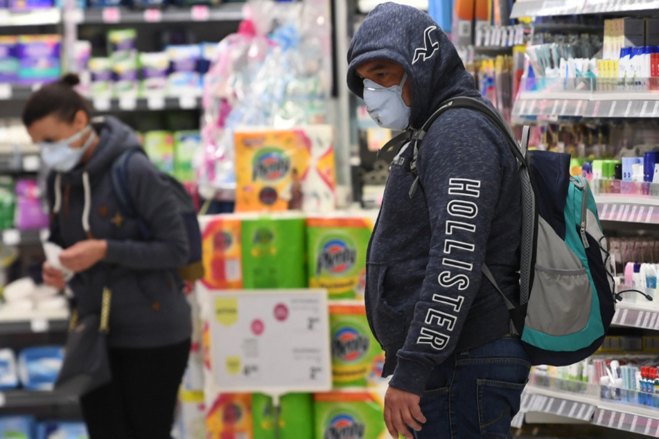 Kunden mit Mundschutz kaufen in einem Supermarkt ein.