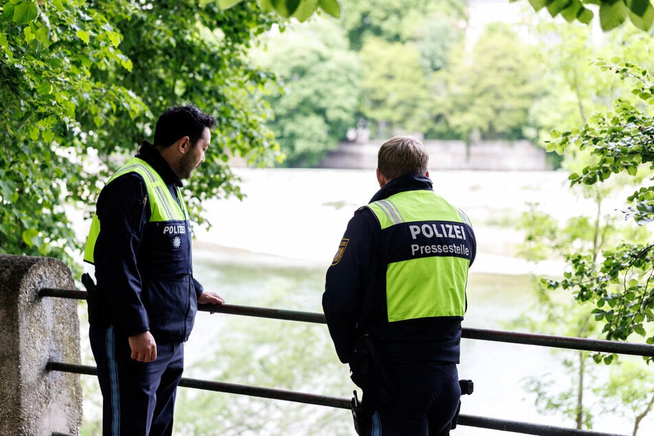 Polizisten stehen am Geländer, an dem ein kleines Kind ins Wasser gefallen ist.