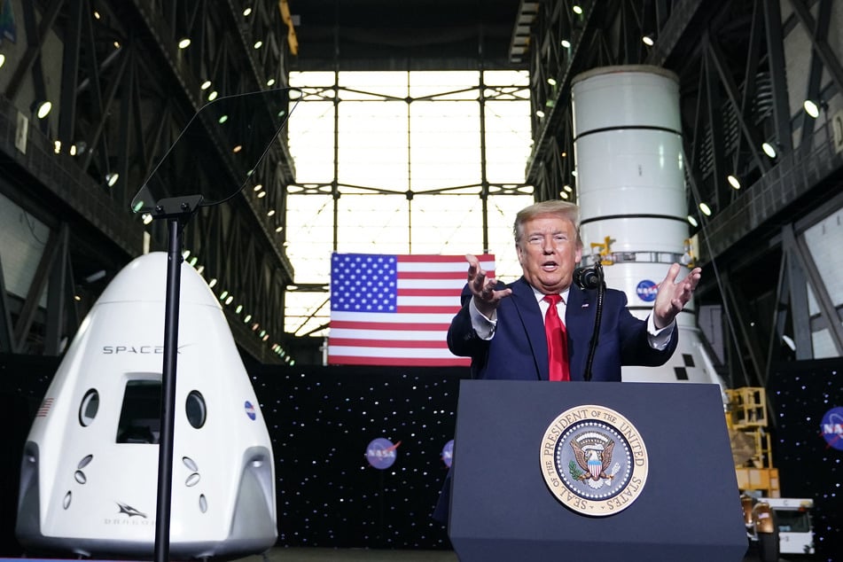 Donald Trump speaks near a SpaceX Crew Dragon capsule at a press briefing after the launch of the SpaceX Falcon 9 rocket and Crew Dragon spacecraft on NASA's SpaceX Demo-2 mission to the International Space Station from NASA's Kennedy Space Center in Cape Canaveral, Florida on May 30, 2020.