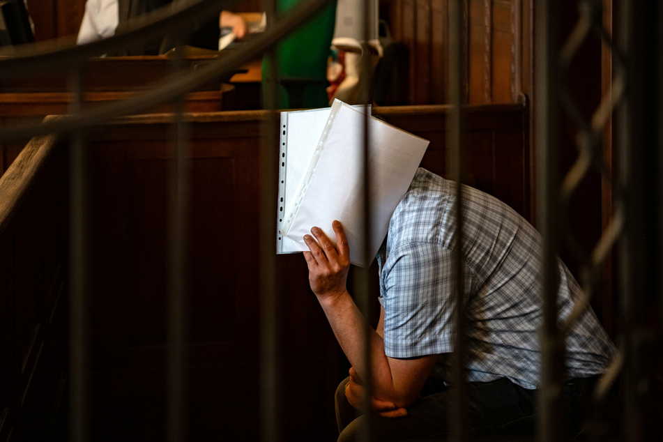 Der Angeklagte verdeckt mit Papierbögen sein Gesicht. Der 50 Jahre alte Mann muss sich seit heute vor Gericht unter anderem wegen sexuellen Übergriffen an Kindern verantworten.