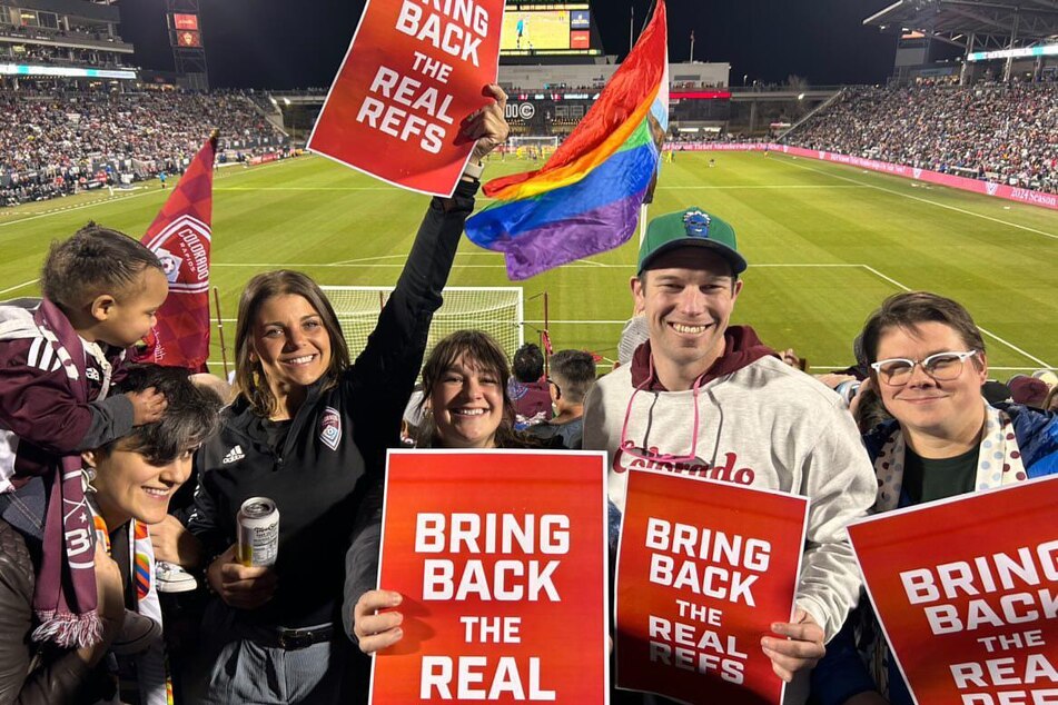 MLS fans wave signs reading "Bring Back the Real Refs" in a show of solidarity with referees on strike.