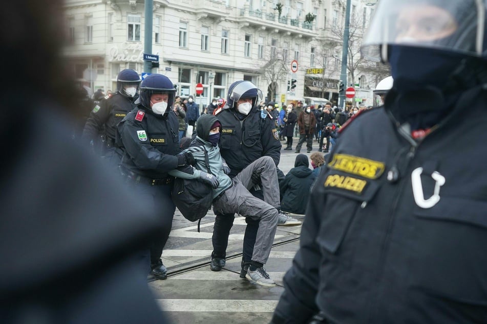 Österreich, Wien: Polizeibeamte tragen einen Teilnehmer einer Demonstration gegen Corona-Maßnahmen weg.