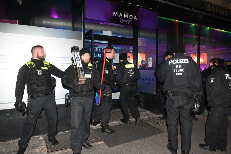Die Berliner Polizei steht mit einem Rammbock und Brecheisen vor der Tür einer Shisha Bar.