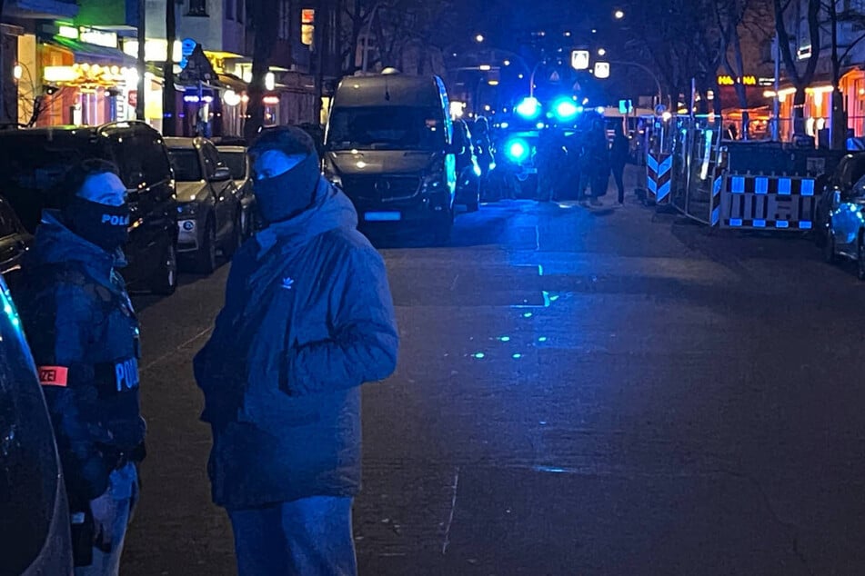 Vermummte Beamte stehen auf der abgesperrten Straße in dem sonst so belebten Kiez.