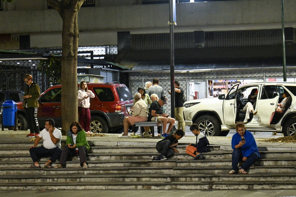 People sit at a public square after an earthquake was felt in Caracas, Venezuela, on September 25, 2025.