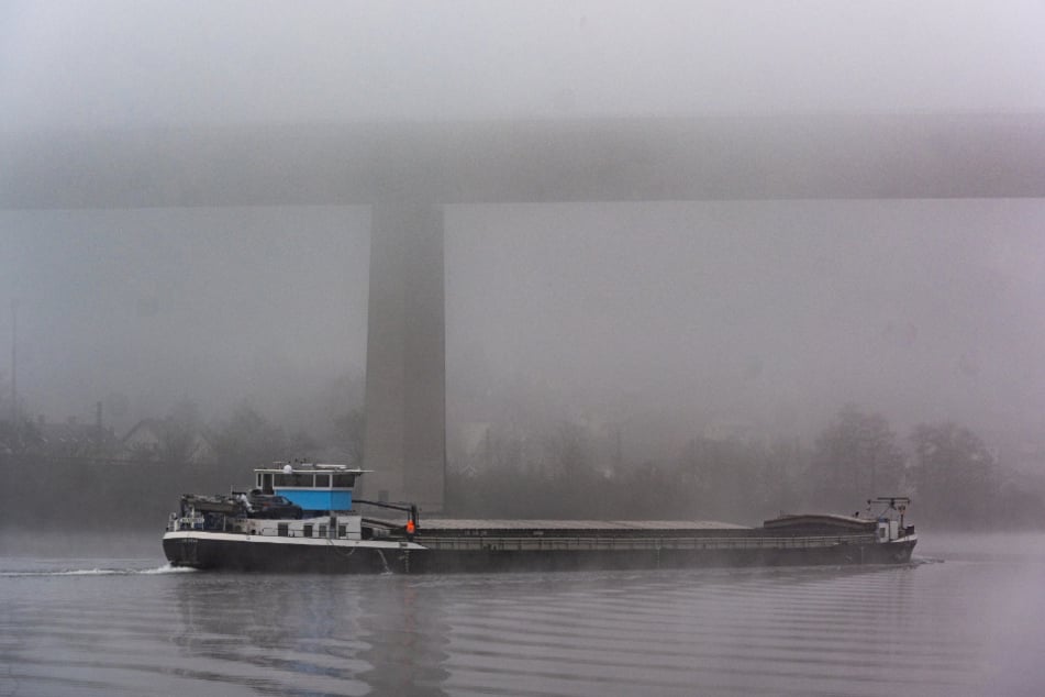 Ein Frachtschiff fährt auf der Donau im Nebel. Die Polizei vermutet, dass das Öl von einem Schiff ausgelaufen ist. (Symbolbild)