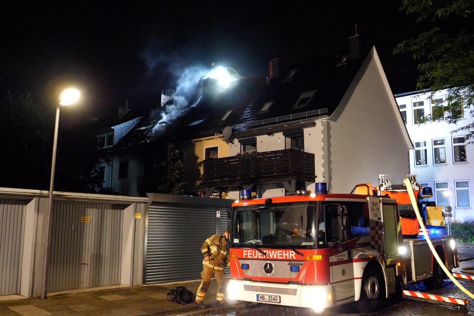 Die Feuerwehr im Einsatz. Rauch sein noch aus dem Dach des zuvor brennenden Hauses.