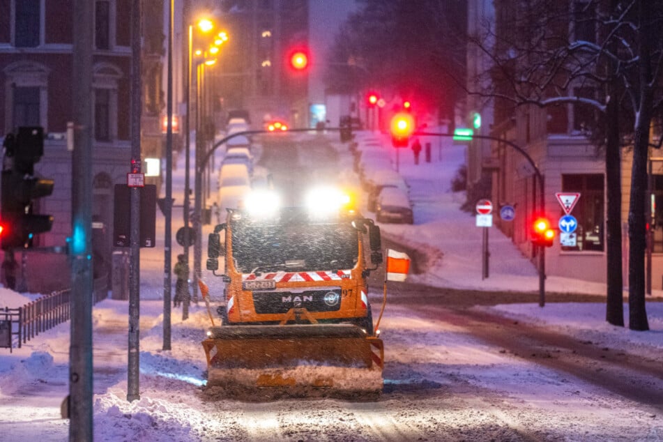 Ein Einsatzfahrzeug des Winterdienstes räumt eine zugeschneite Straße.