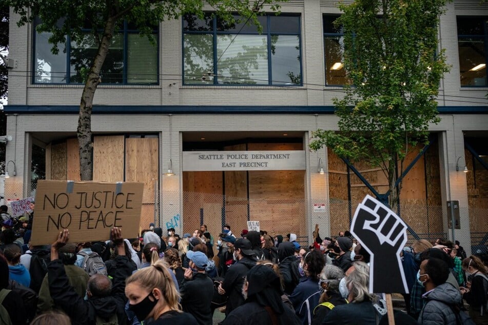 Demonstrators hold a rally and teach-in outside of the Seattle Police Departments East Precinct, which has been boarded up and protected by fencing, on June 8, 2020.