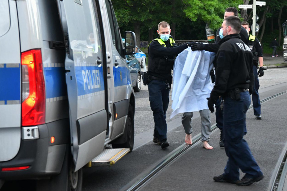 Polizisten führen den Verdächtigen ab.
