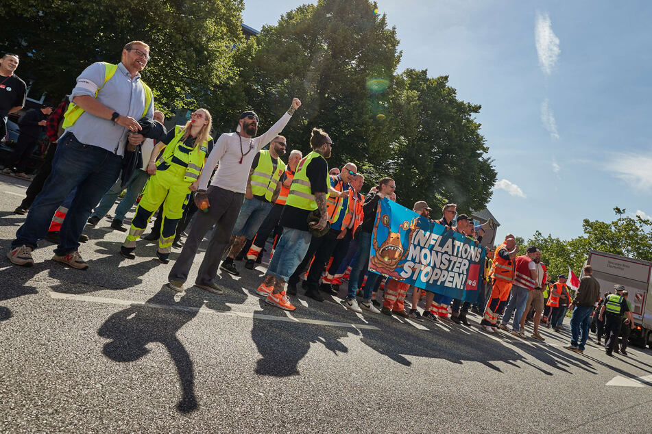 Hafenarbeiter tragen während einer Kundgebung auf der Fuhlsbüttler Straße ein Transparent mit der Aufschrift "Inflationsmonster stoppen!".