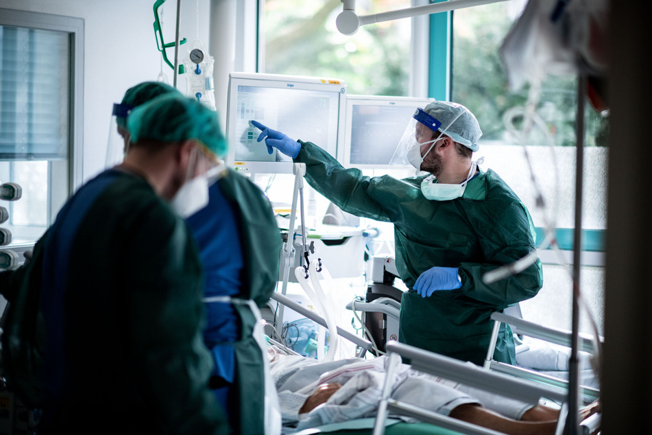 Pfleger in Schutzkleidung behandeln einen Patienten mit Corona-Infektion auf einer Intensivstation.