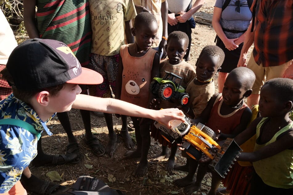 Ole (11) überreicht seinen Plastikbagger an die Kinder.