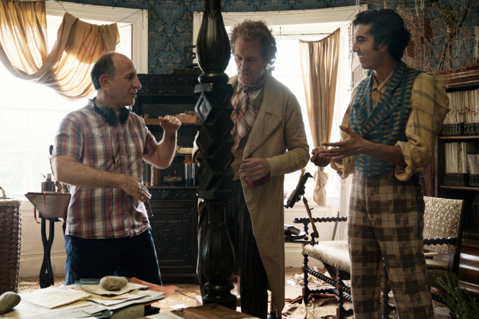Regisseur Armando Iannucci (l.) gibt Hugh Laurie (M., Mr. Dick) und Dev Patel (David Copperfield) am Filmset Anweisungen für die nächste Szene.