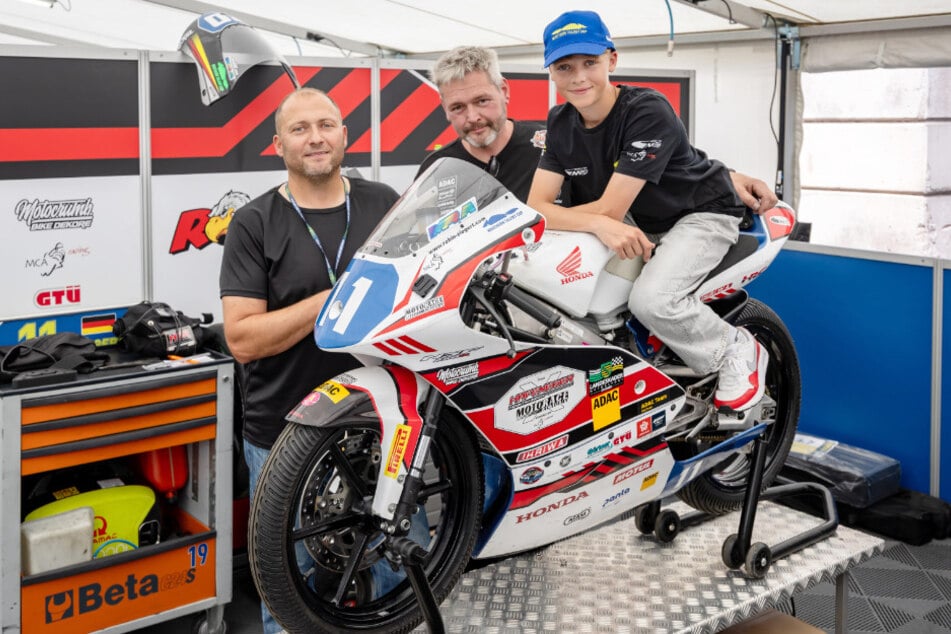 Robin en su máquina, una Honda NSF250R, junto al jefe de mecánicos Mike Lischka (52, d.) y su padre Steffen Sachse (47, i.).