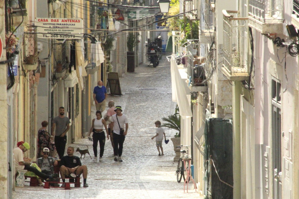 Menschen gehen eine Straße im Lissabonner Stadtteil Setubal entlang.