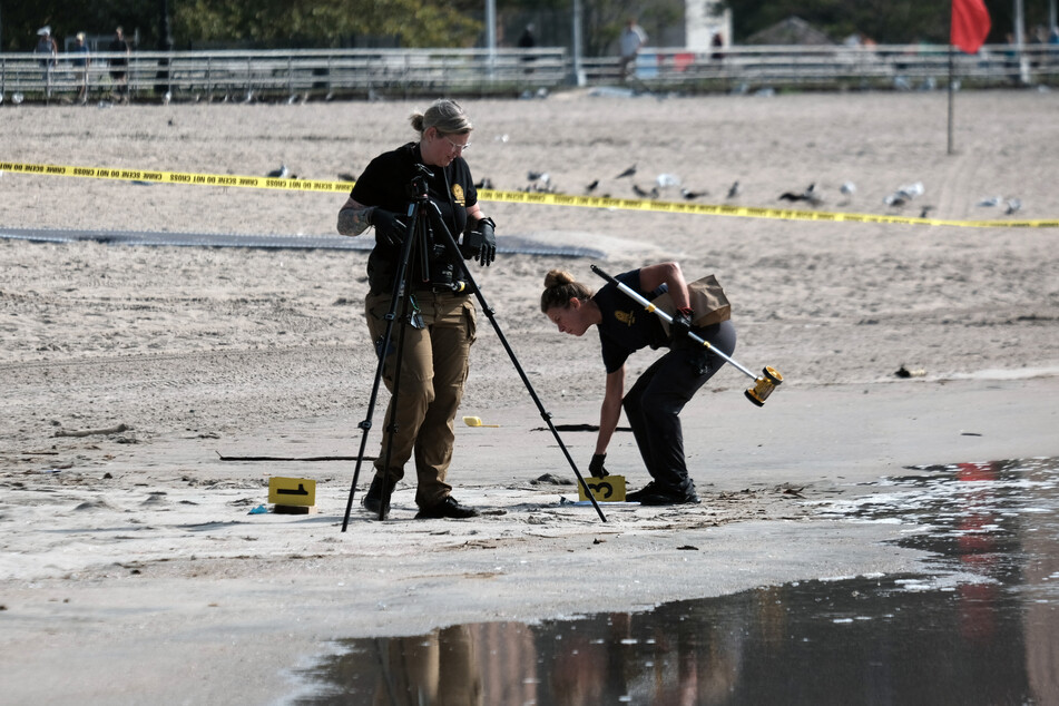 Police work along a stretch of beach at Coney Island which is now a crime scene after a mother was suspected of drowning her children in the ocean on September 12.