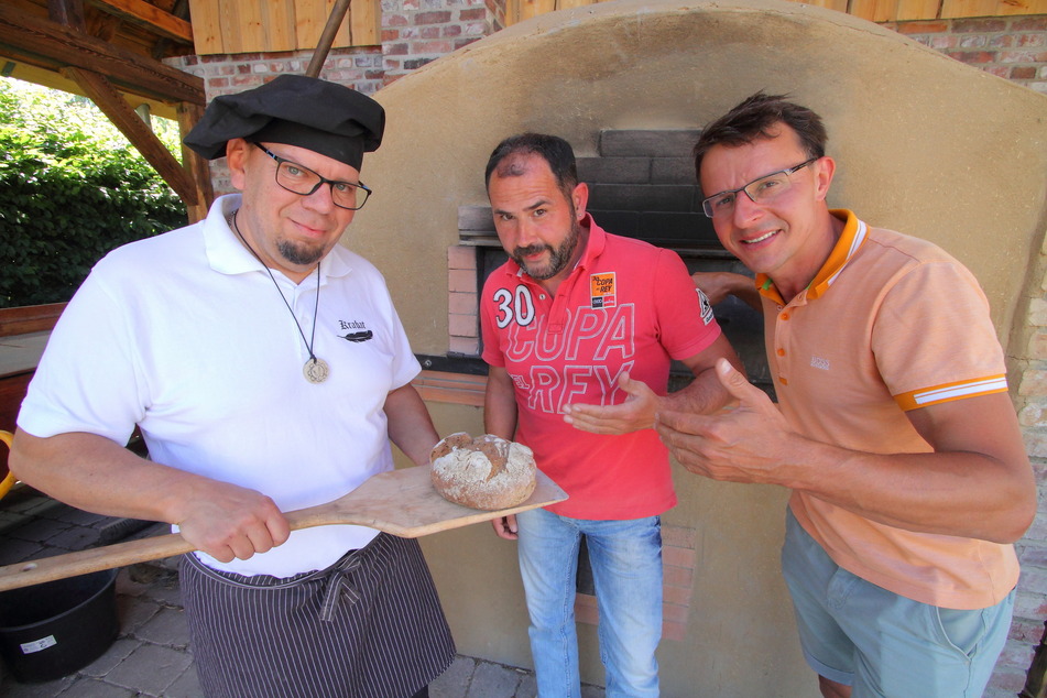Bäcker Rico Ziegenbalg (51, v.l.) bereitet mit Regisseur Alexander Siebecke (49) und Mühlen-Chef Tobias Zschieschick (45) frisches Steinofenbrot im neuen Backhaus zu.