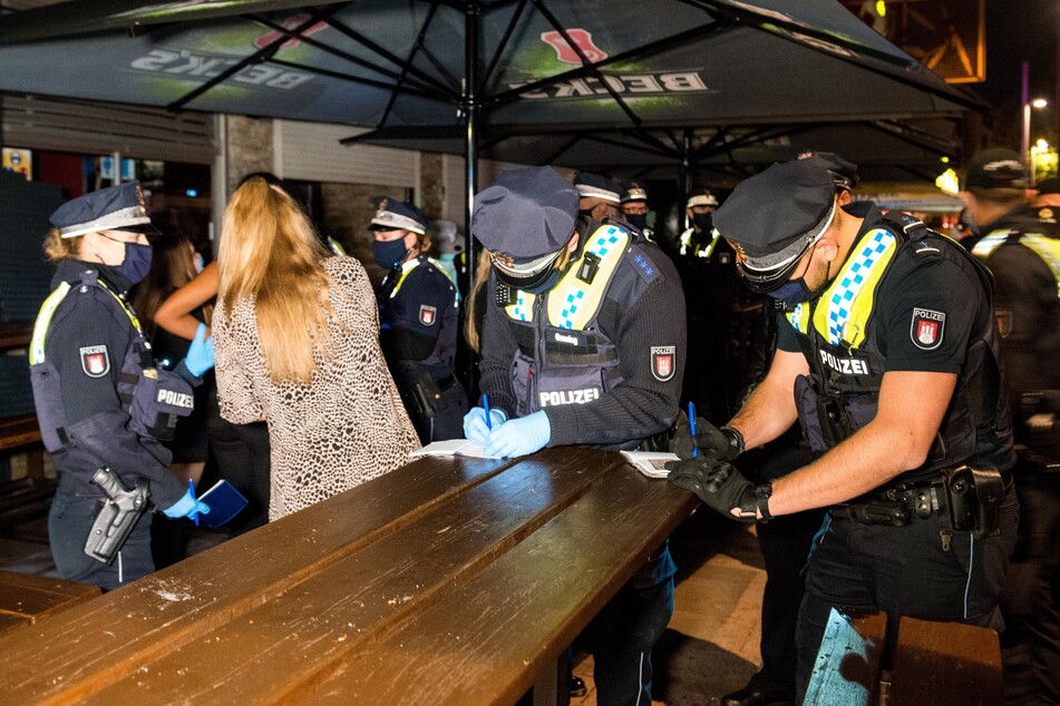 Polizisten nehmen vor der Disco auf der Reeperbahn die Personalien von Besuchern auf.