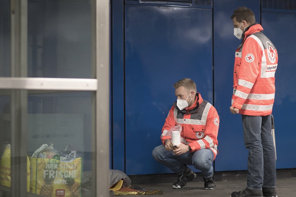 Die Rettungssanitäter Tobias (l.) und Martin sprechen mit einem Mann, der in einer Unterführung sitzt.