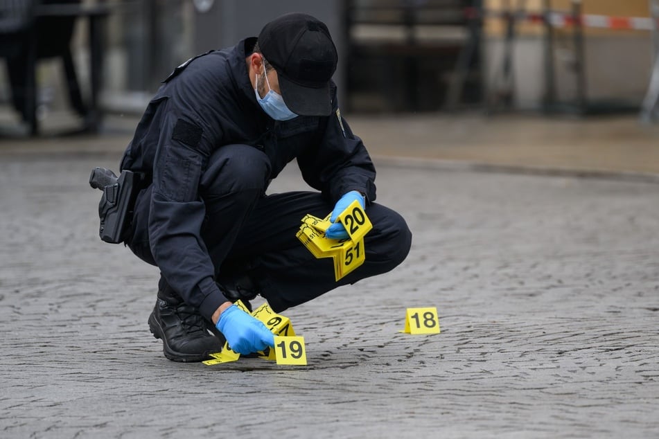 Ein Polizeibeamter stellt in der Fußgängerzone Zahlentafeln auf, überall da, wo die mörderische Fahrt Spuren hinterließ.