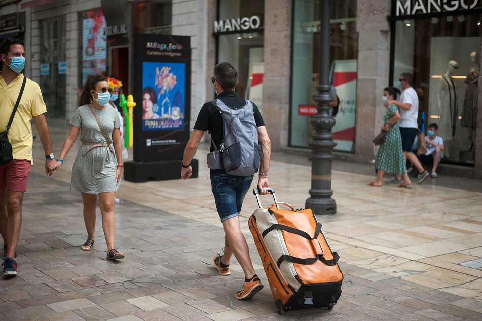 Spanien, Malaga: Ein Tourist trägt seine Taschen durch die Straße Marques de Larios.