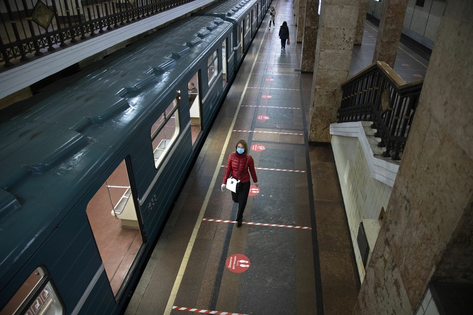 Reisende mit medizinischen Mundschutzmasken gehen am Gleis eines U-Bahnhofs entlang. Seit dem 12.05.2020 ist das Tragen von Gesichtsmasken und Latexhandschuhen für Personen, die die öffentlichen Verkehrsmittel in Moskau benutzen, Pflicht.